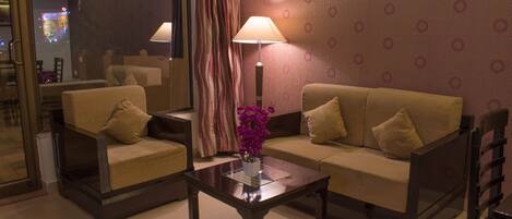 Une chambre d’hôtel avec un canapé, un fauteuil et une table avec une lampe.
