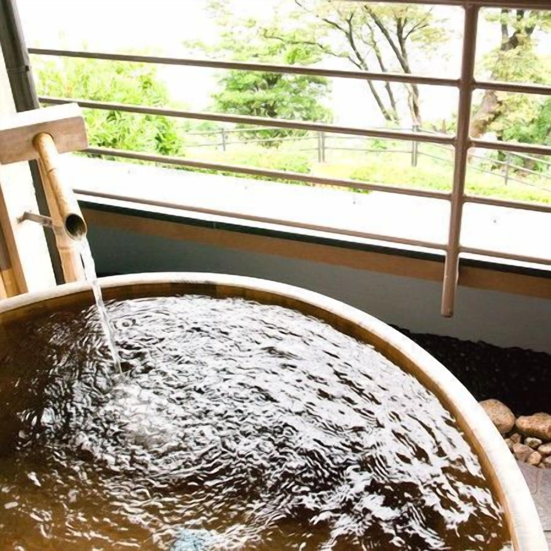 A circular water feature with a wooden structure on top, viewed through a window with metal bars.