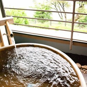 A circular water feature with a wooden structure on top, viewed through a window with metal bars. - Aburaya Annex Nagomitei (Ine)