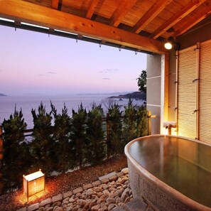 A hot tub with a view of the sea, surrounded by trees and a stone pathway. - Aburaya Annex Nagomitei (Ine)