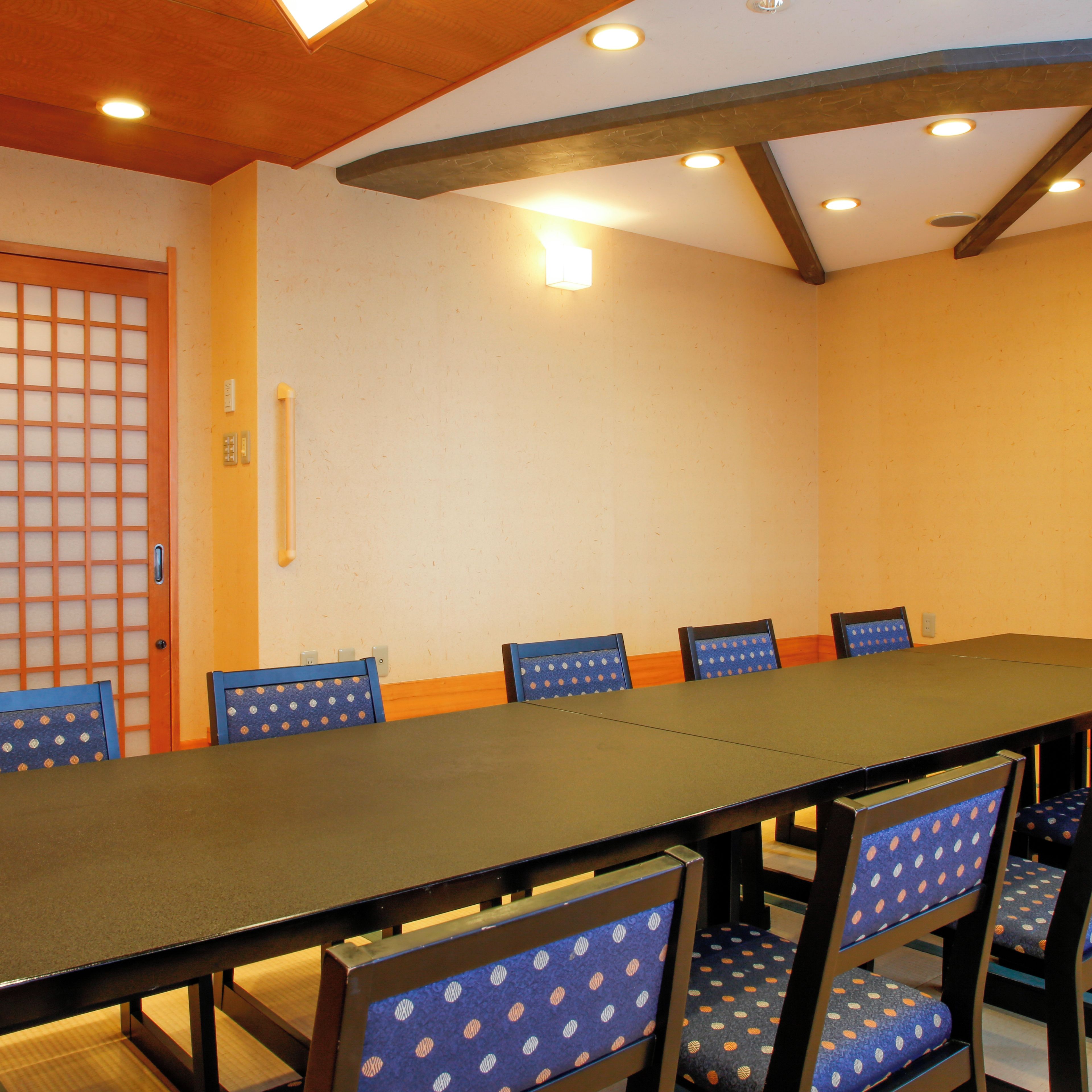 A conference room with a long table and six chairs with blue upholstery.