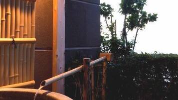 A hot tub with a bamboo fence and a wooden railing.