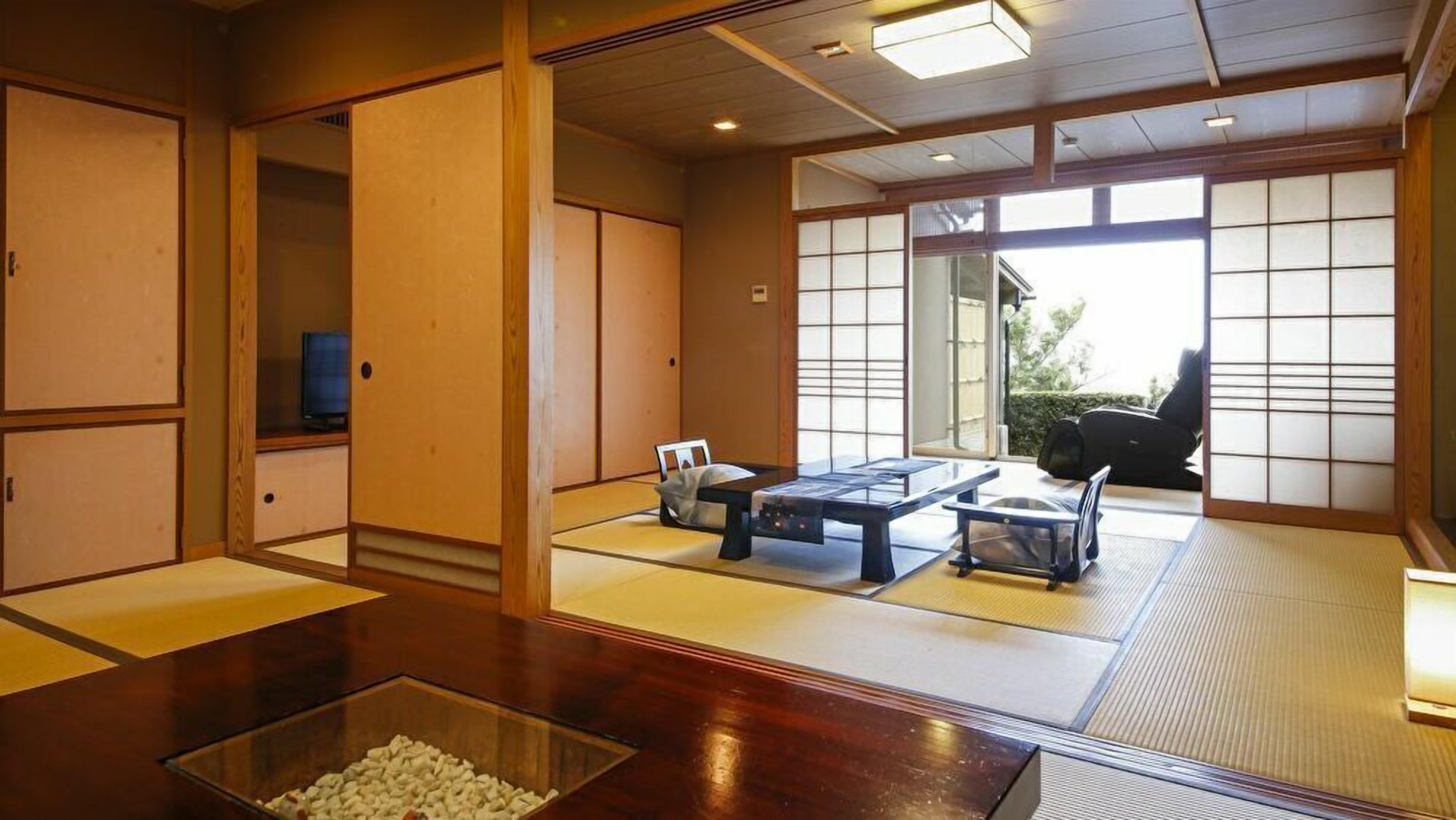 Una habitación tradicional japonesa con suelo de tatami, puertas correderas y una mesa baja con un recipiente de vidrio transparente.
