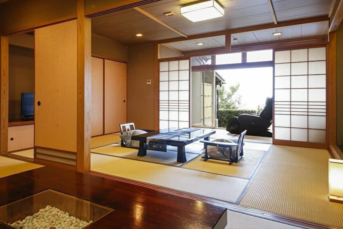 A traditional Japanese room with tatami flooring, sliding doors, and a low table with a clear glass container.