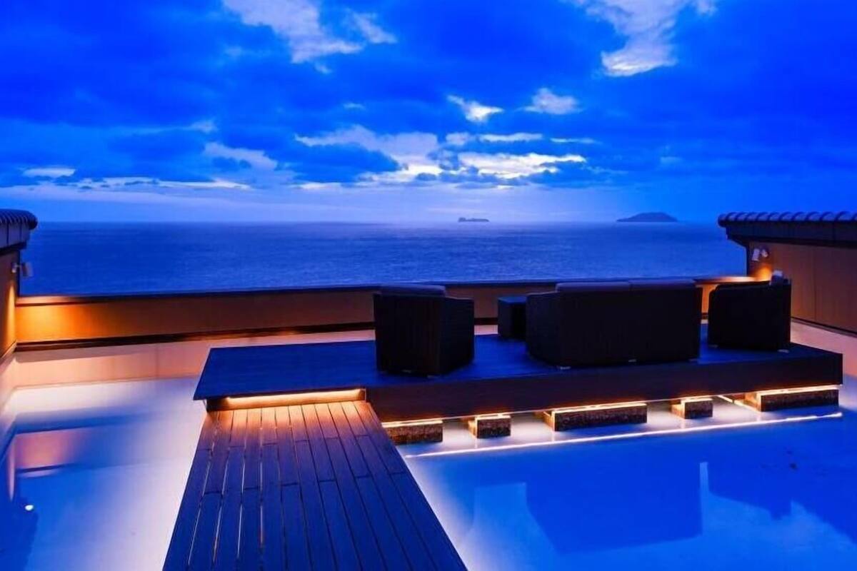 A rooftop terrace with a pool, seating area, and a view of the ocean.