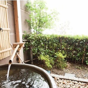 A traditional Japanese onsen with a stone bath, bamboo structures, and a garden with a wooden fence and greenery. - Aburaya Annex Nagomitei (Ine)