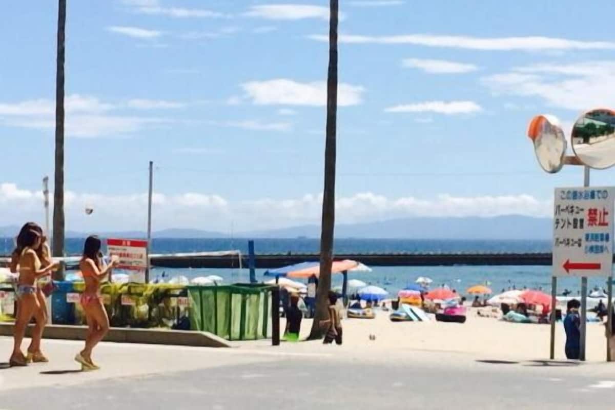 A beachside location with palm trees, a clear sky, and a sign with Japanese text.