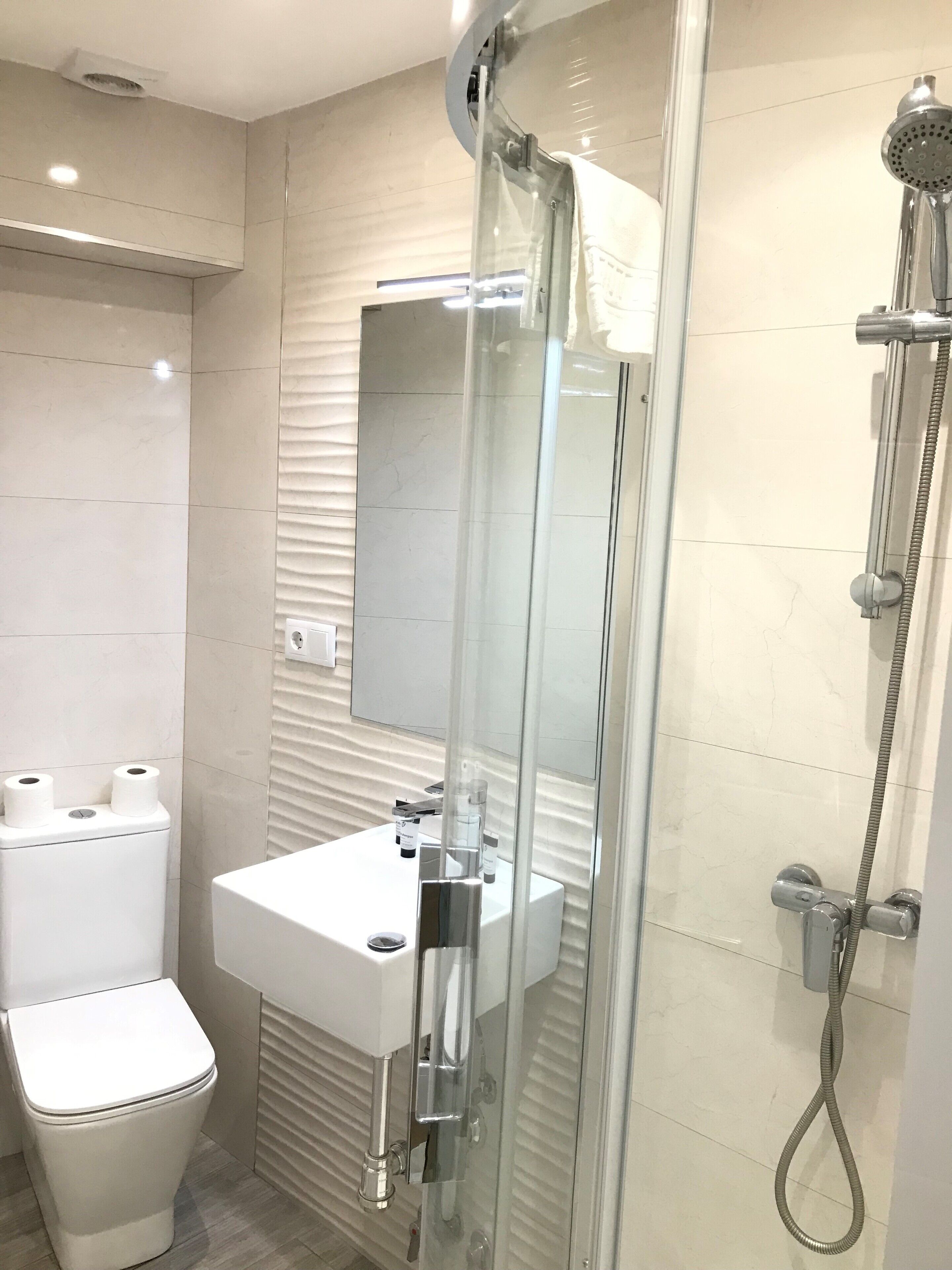 Une salle de bain moderne avec une douche à parois de verre, un lavabo blanc et des toilettes.