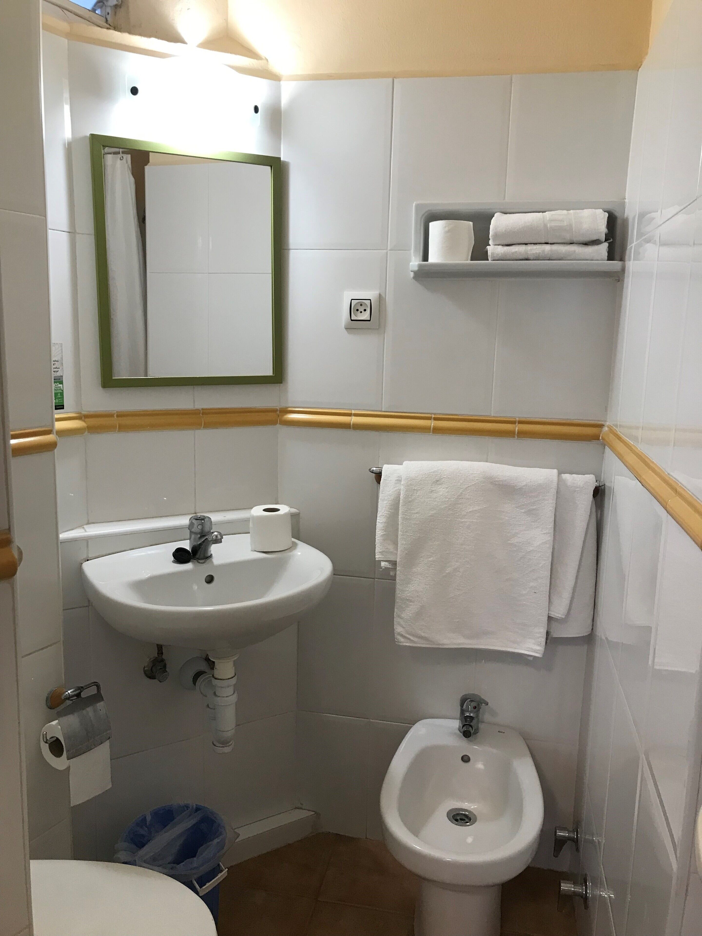 Un baño con lavamanos, espejo, toallero y bidé.