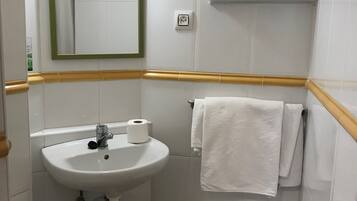Un baño con lavamanos, espejo, toallero y bidé.