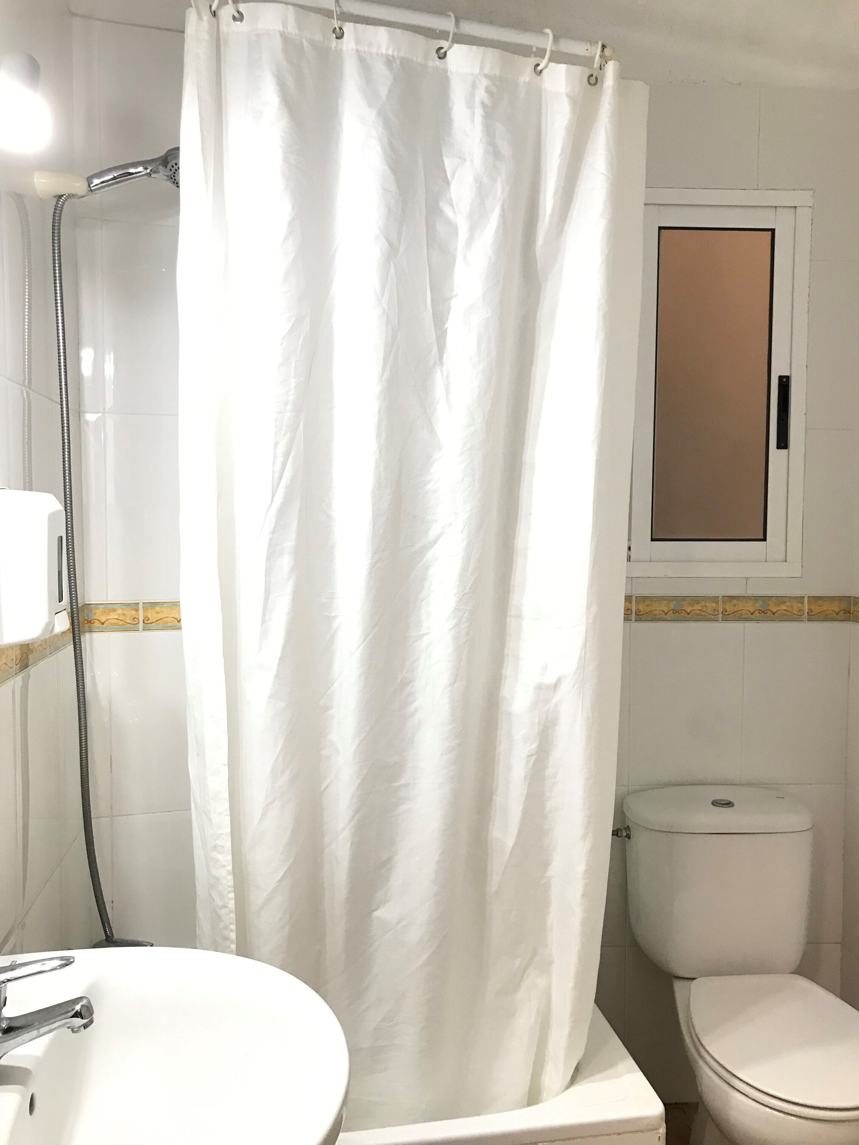 A bathroom with a shower curtain, a toilet, and a sink.