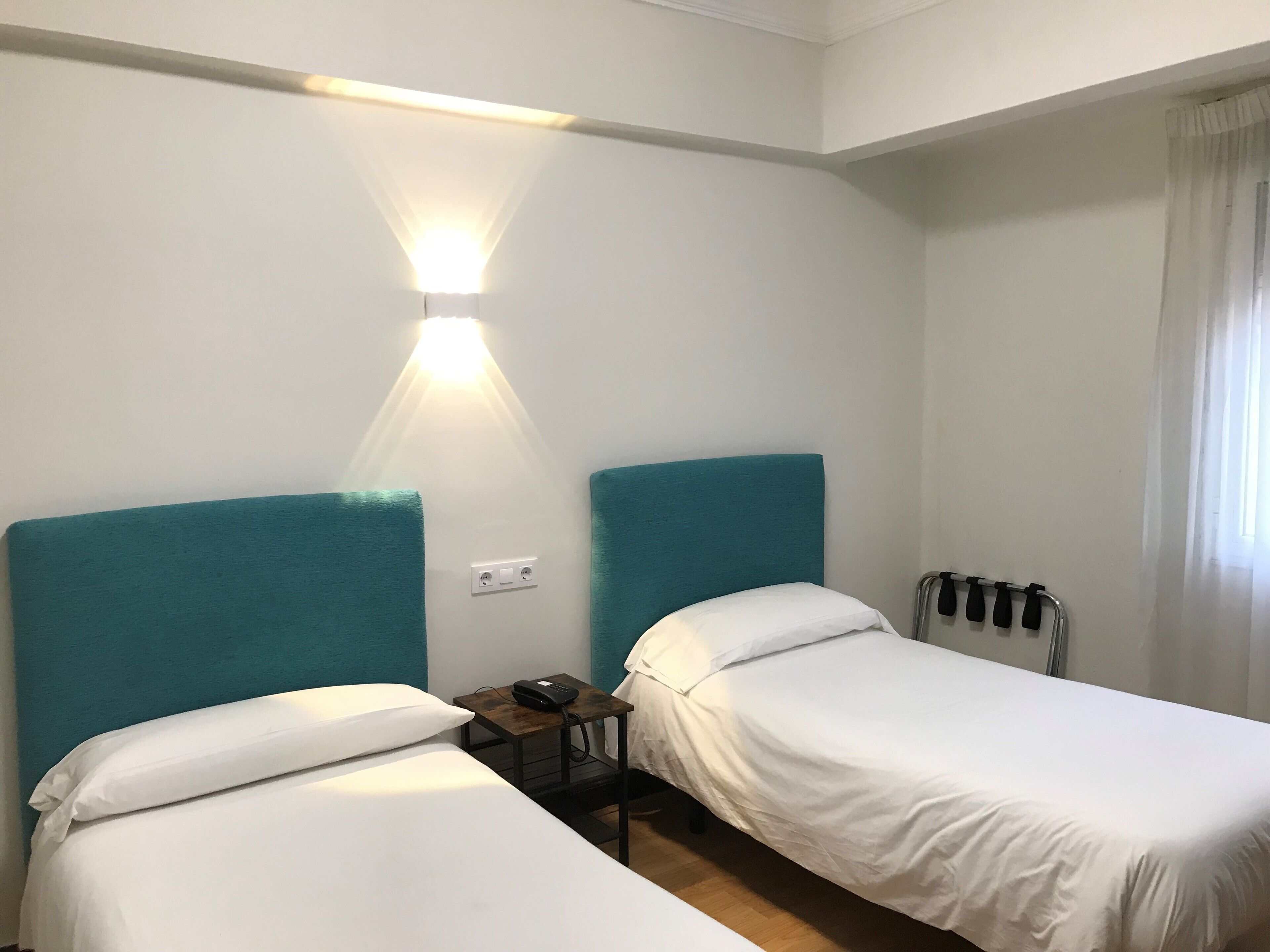 Ein Hotelzimmer mit zwei Einzelbetten, einem Nachttisch mit Telefon und einer Wandleuchte.