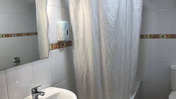 Un baño con lavamanos blanco, inodoro y cortina de ducha.