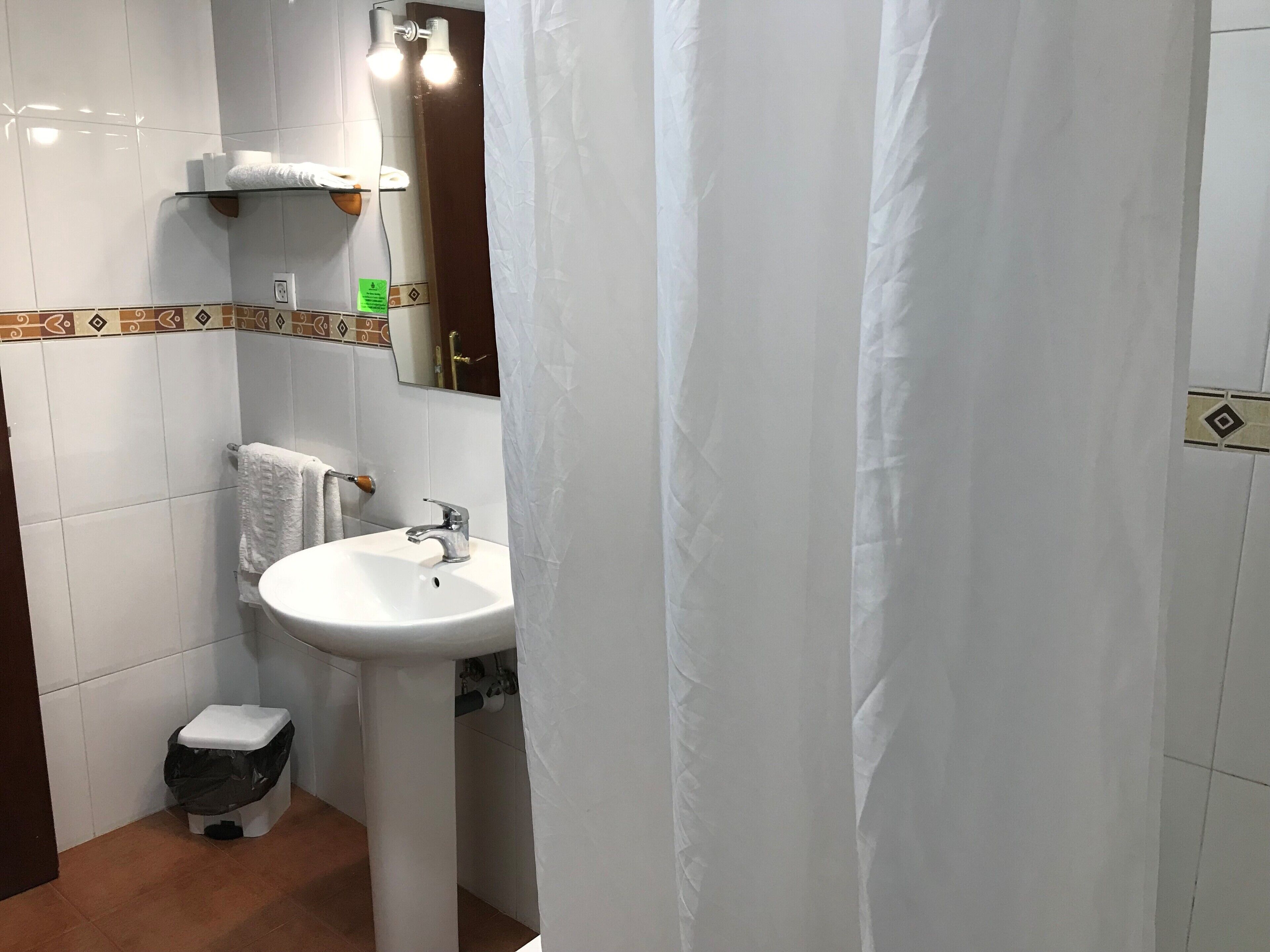 Een badkamer met een wit wastafel, toilet en douchegordijn.