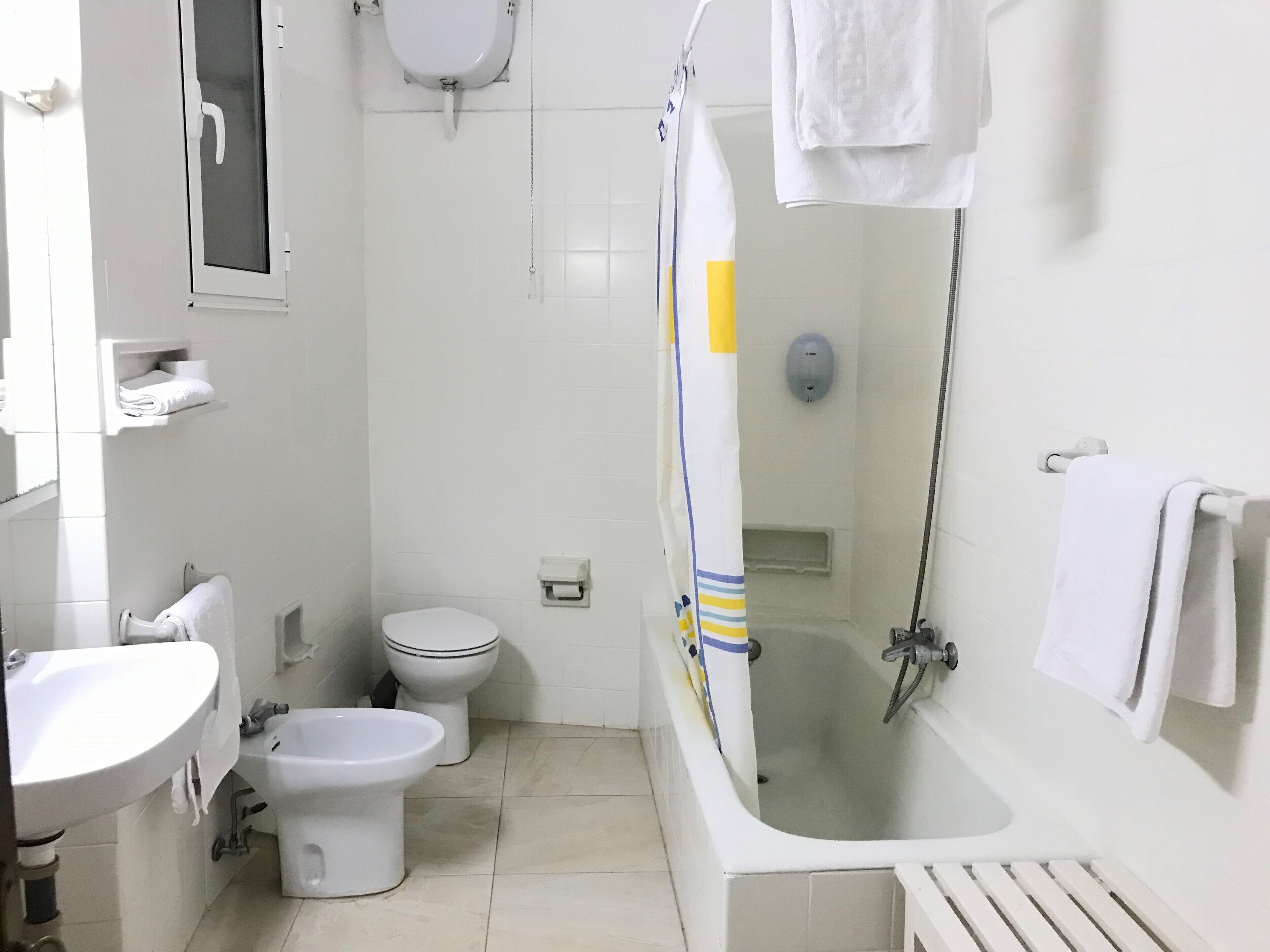 Un baño con lavamanos, dos inodoros, bañera y ducha.