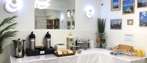 A hotel room with a breakfast bar, a coffee maker, a toaster, and a fruit display.
