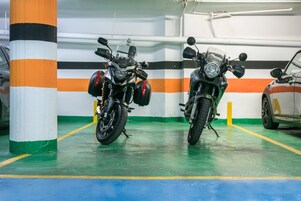 Un estacionamiento con dos motocicletas aparcadas junto a un pilar.