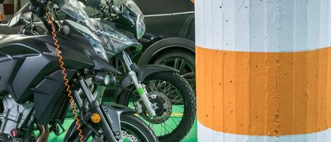 A motorcycle with a visible orange cable, a black and white striped wall, and a green floor.