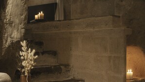 Een stenen trap met kaarsen, een vaas met gedroogde bloemen en een rustieke muur.