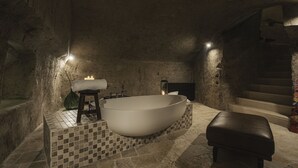 Een moderne badkamer met een vrijstaand bad, een klein krukje, een wastafel en een lantaarn.
