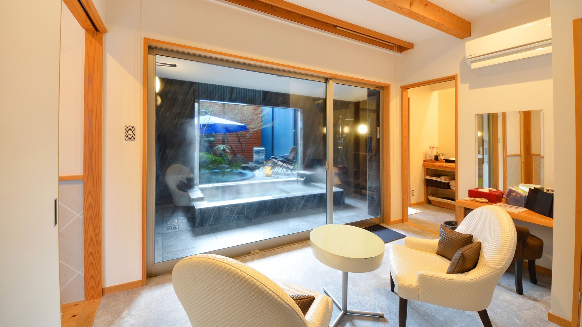 A modern interior with a sliding glass door leading to a patio, a round table, and a comfortable chair.