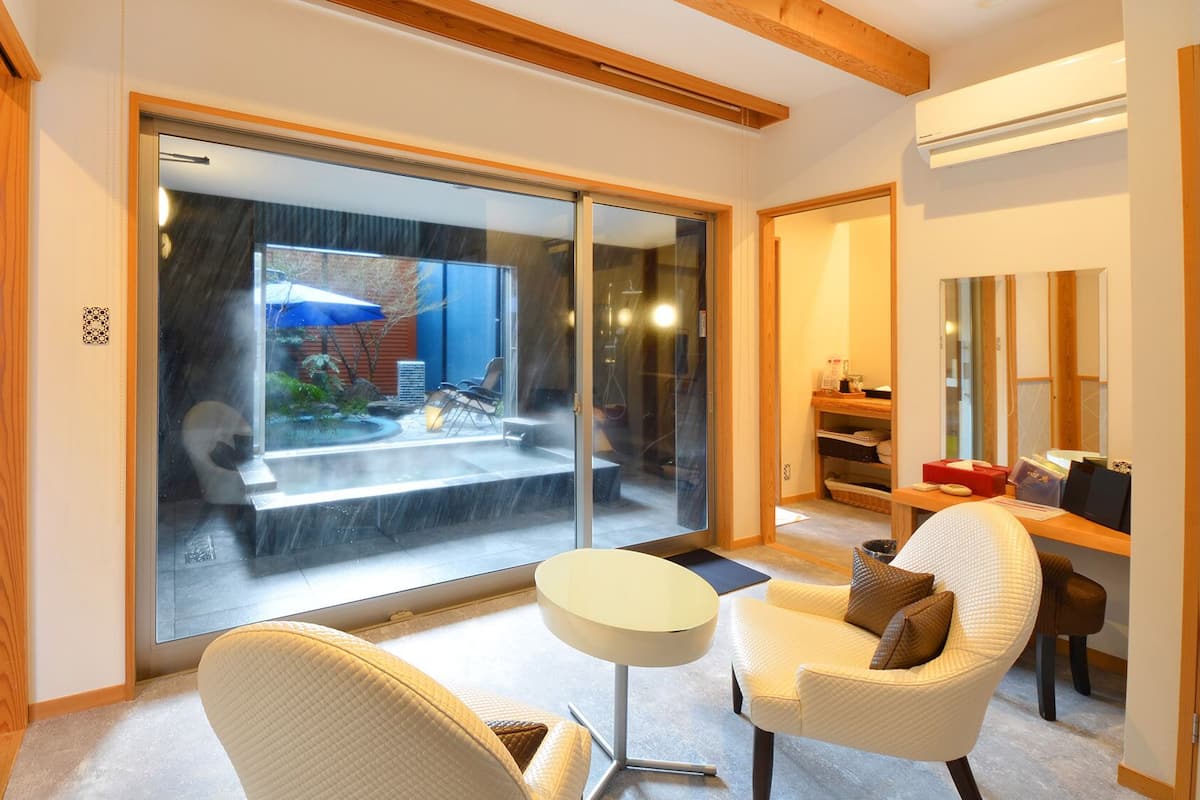 A modern interior with a sliding glass door leading to a patio, a round table, and a comfortable chair.