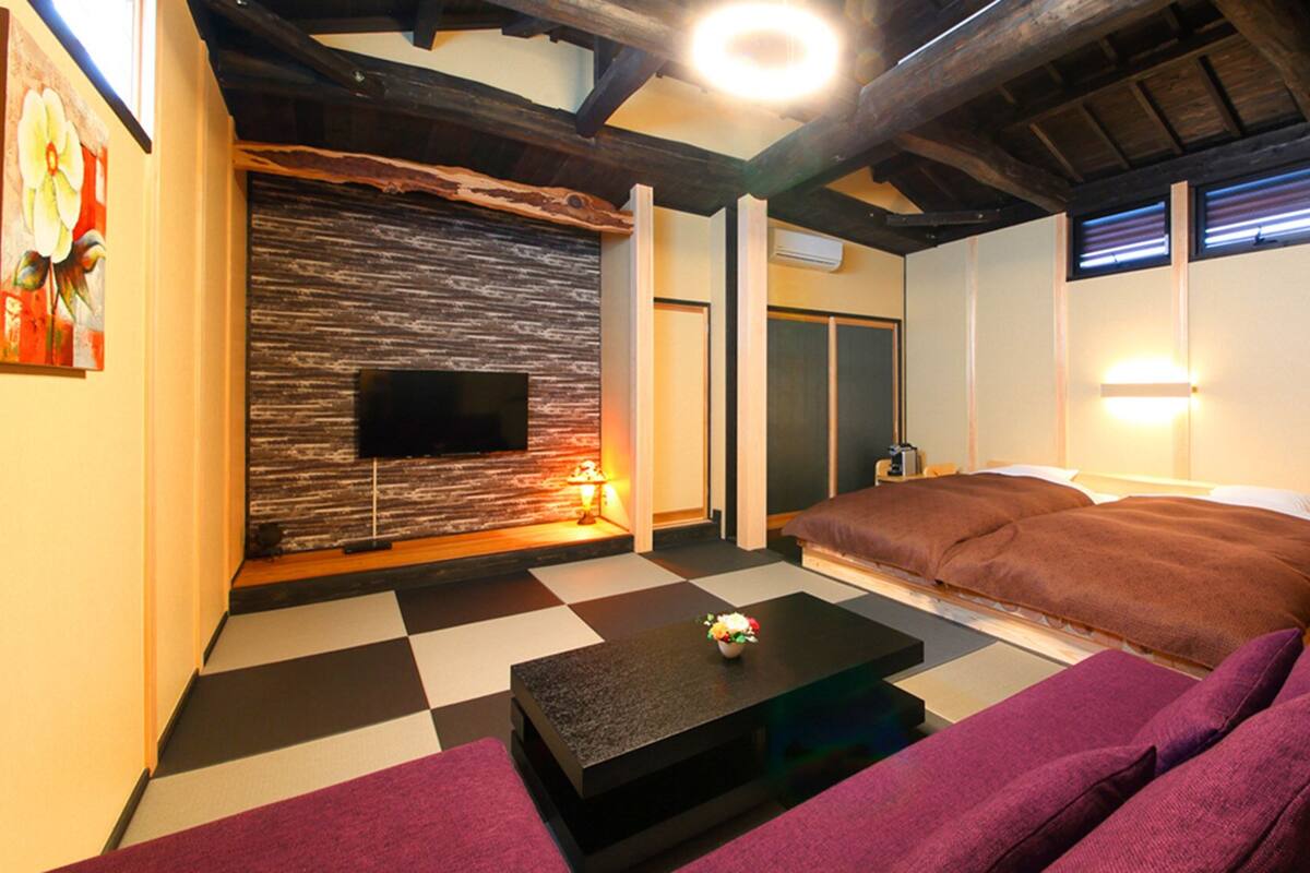 A room with a checkered floor, a sofa, a flat-screen TV, and a wooden ceiling.