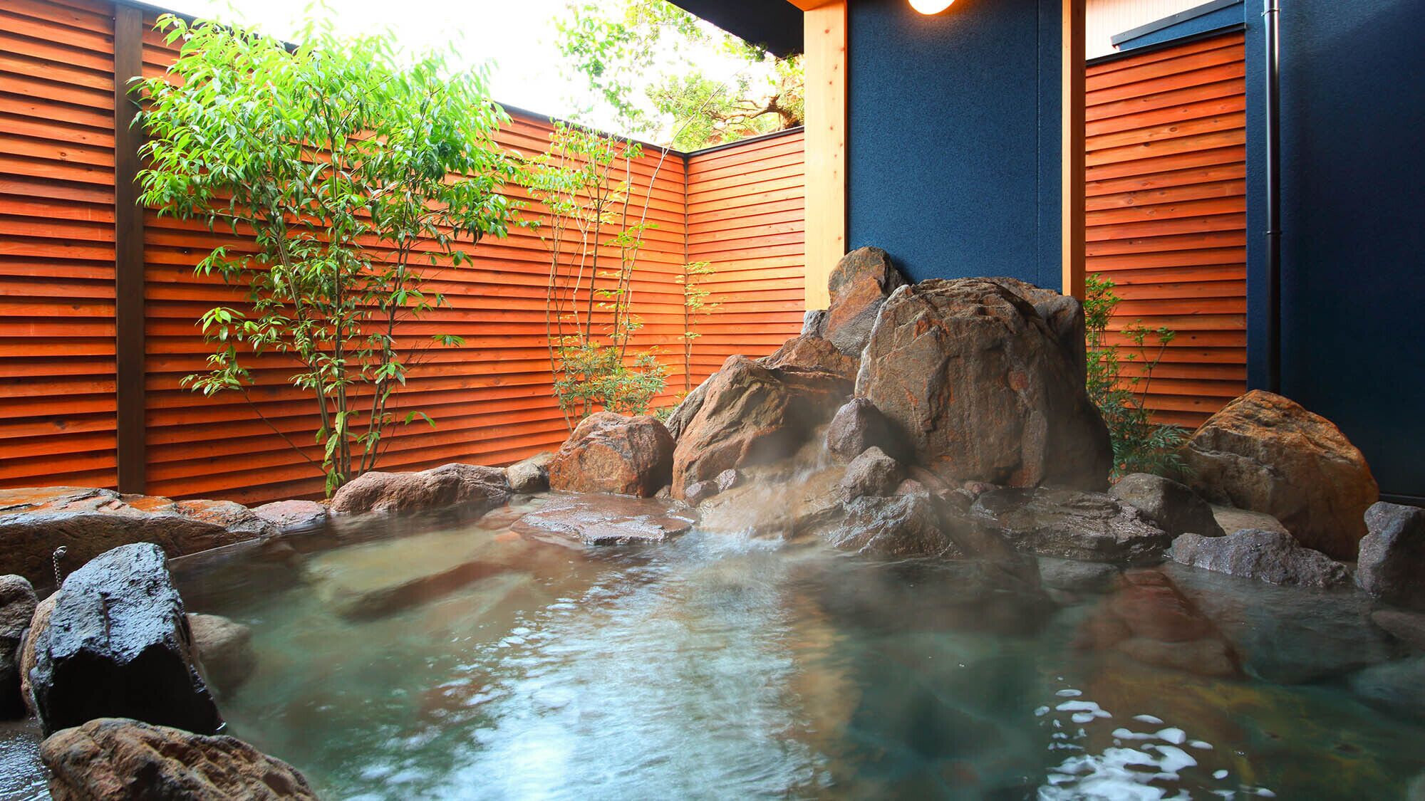 A hot spring with rocks and a wooden fence.