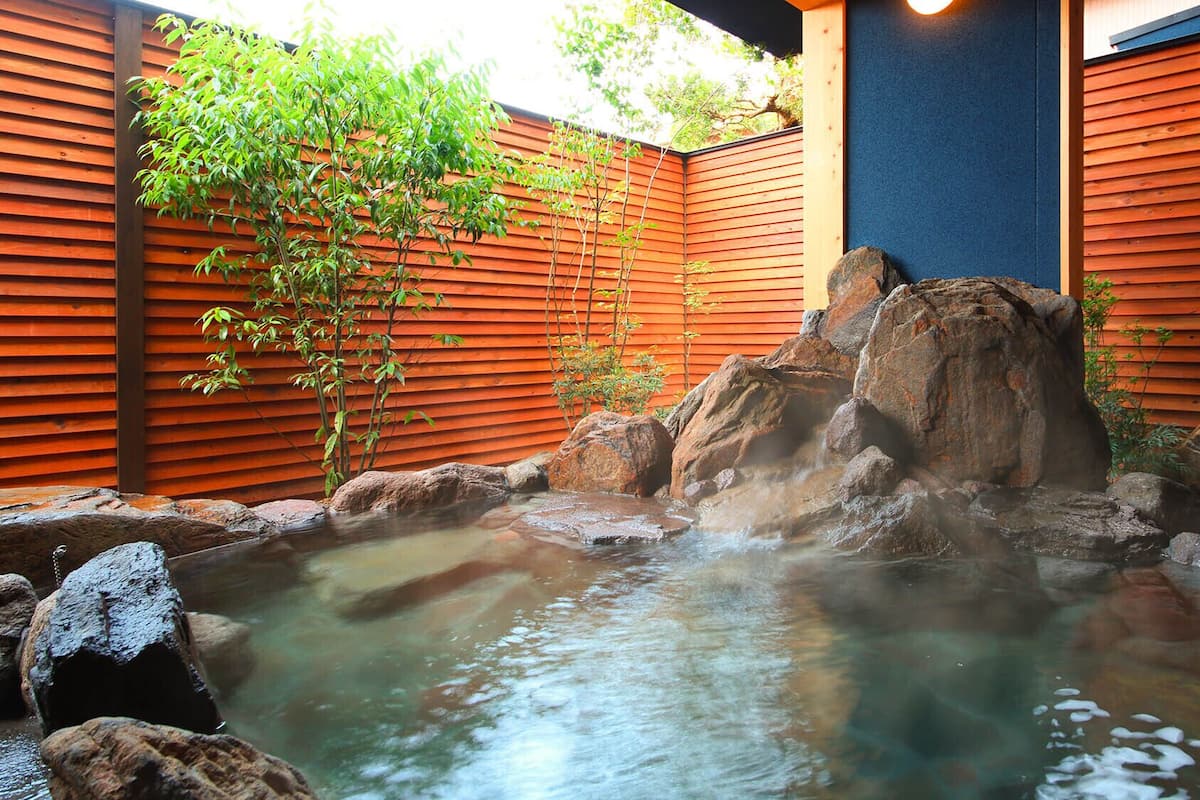 A hot spring with rocks and a wooden fence.