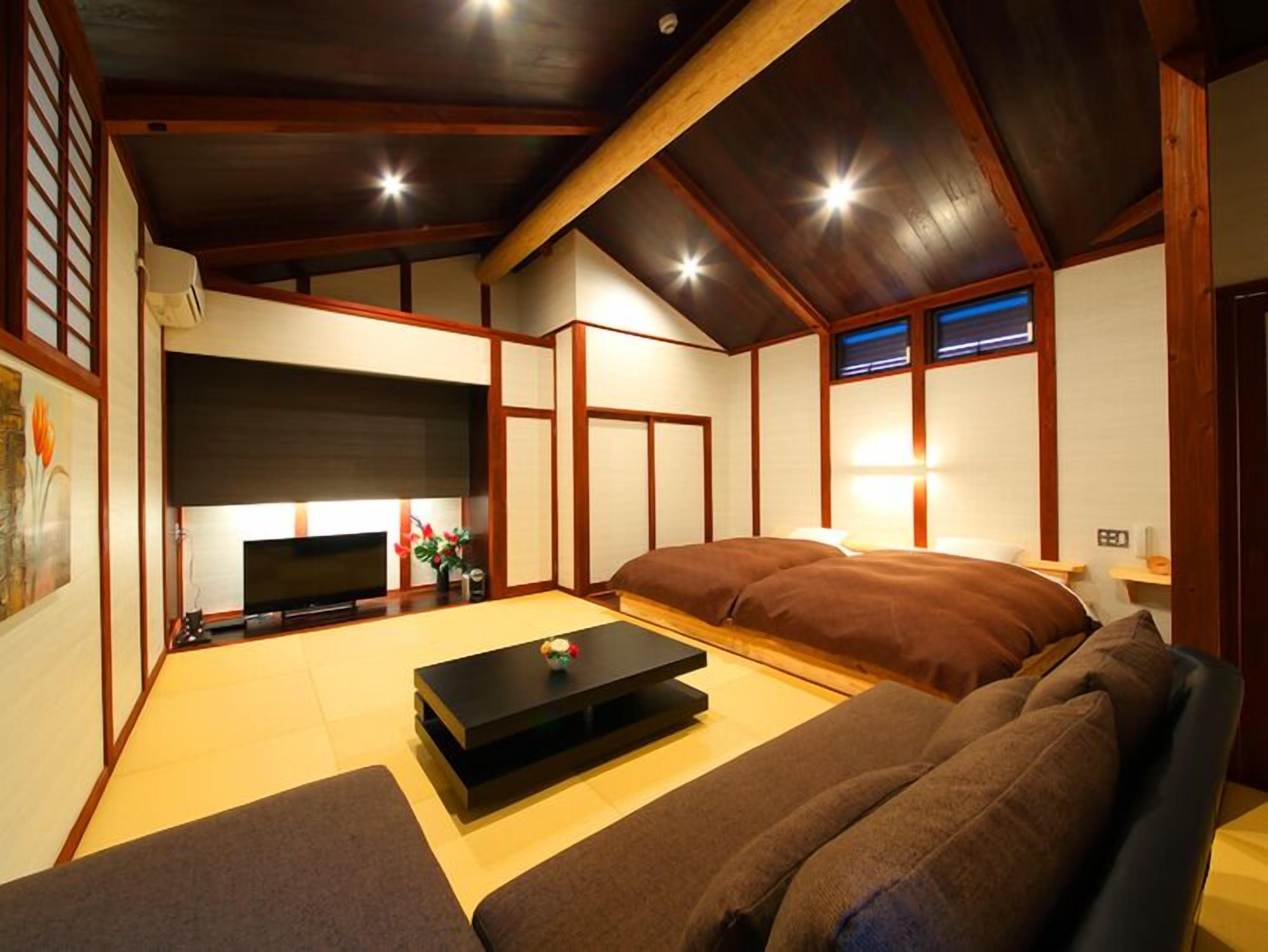 A traditional Japanese-style room with tatami flooring, a low ceiling, and wooden beams.