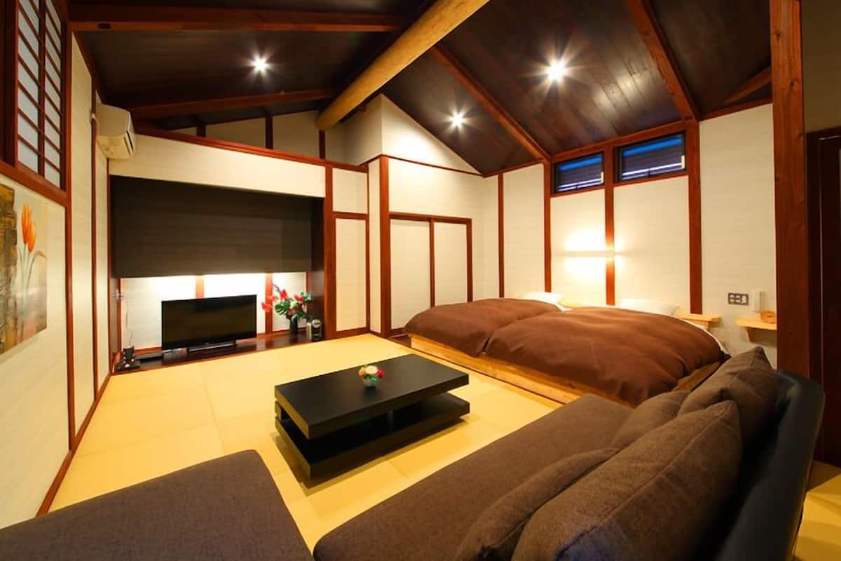A traditional Japanese-style room with tatami flooring, a low ceiling, and wooden beams.