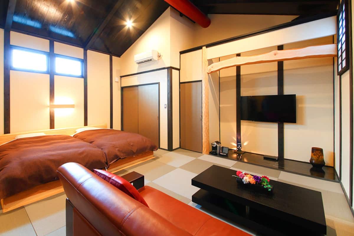 A hotel room with a bed, a sofa, a TV, a small table, and a wardrobe.