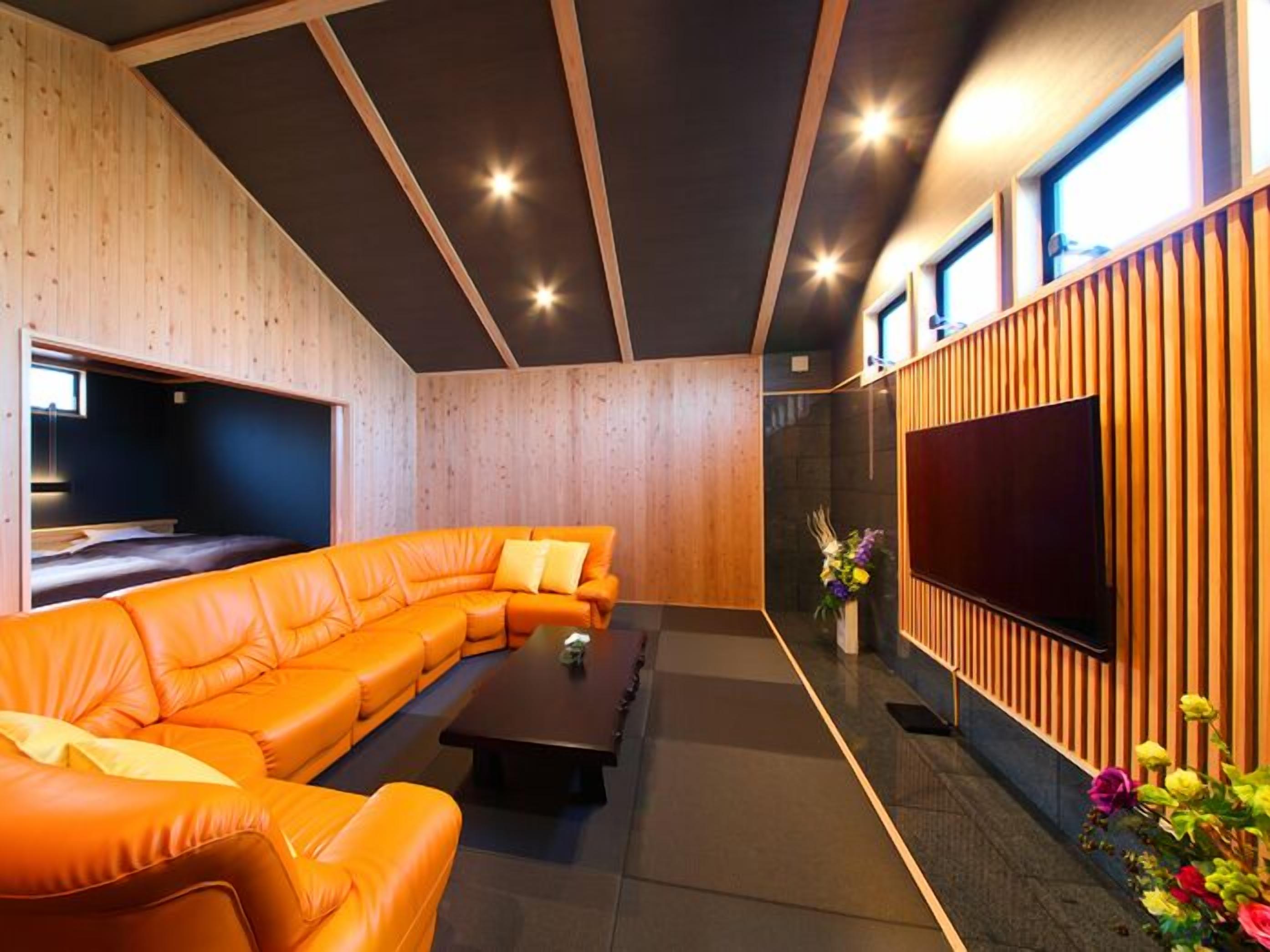 A modern living room with a sectional sofa, a flat-screen TV, and wooden paneling.