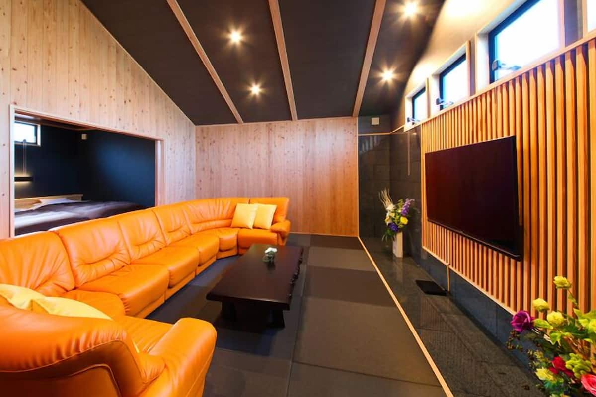 A modern living room with a sectional sofa, a flat-screen TV, and wooden paneling.
