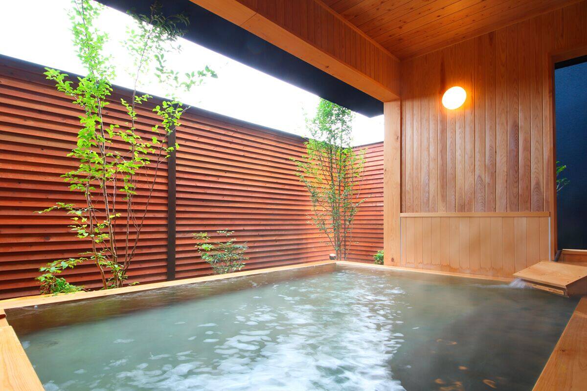 A hot spring area with wooden walls, a wooden bench, and a small waterfall feature.