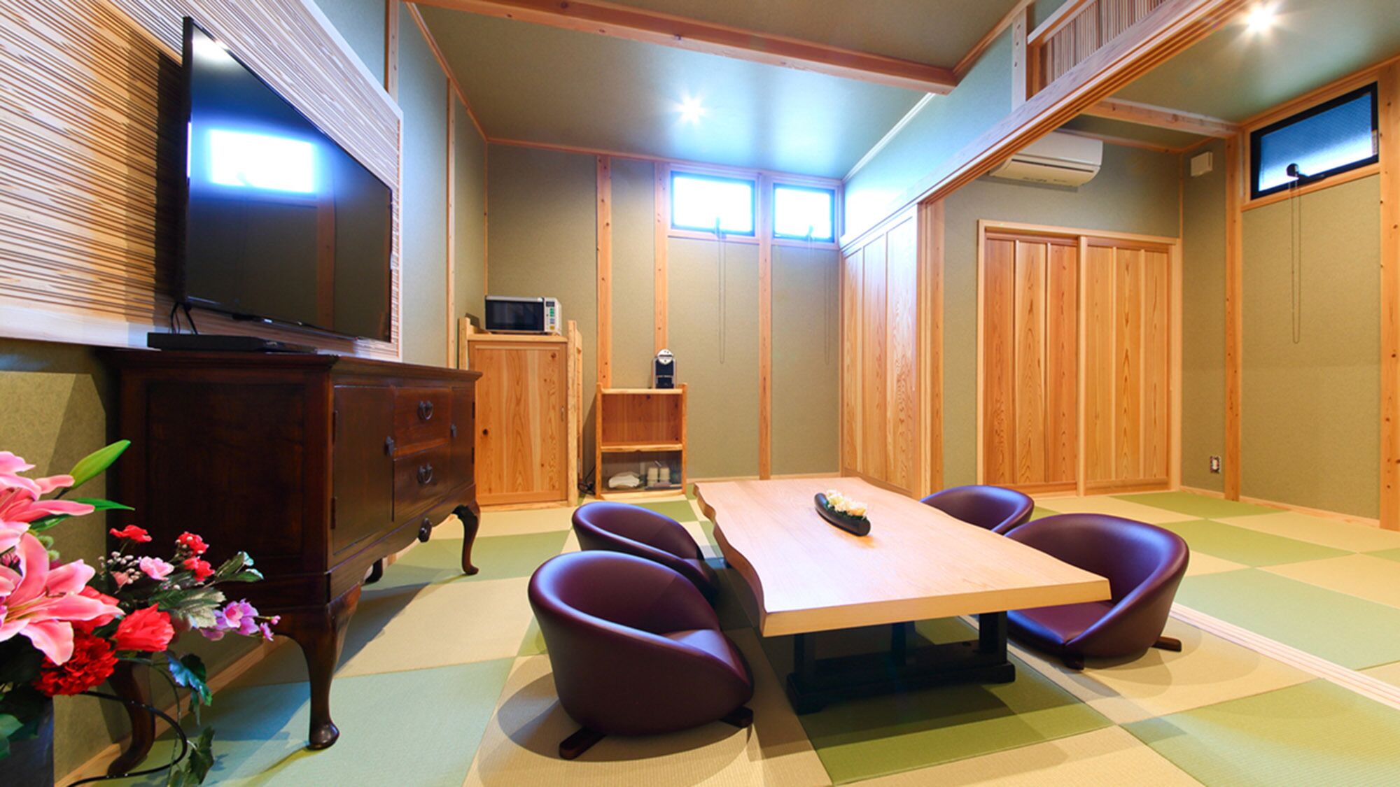 A room with a wooden table, purple chairs, a TV, a microwave, and a cabinet.