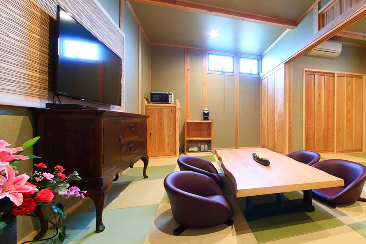 A room with a wooden table, purple chairs, a TV, a microwave, and a cabinet.