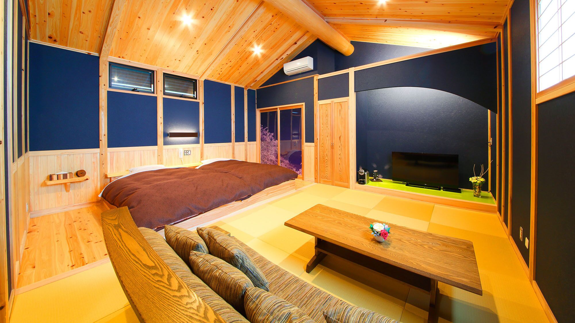 A cozy room with a bed, a sofa, a table, and a TV.