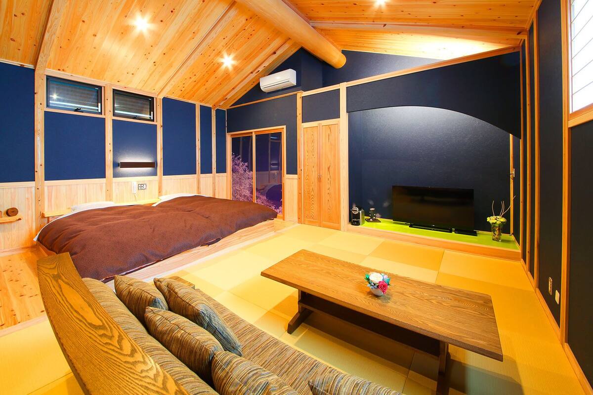 A cozy room with a bed, a sofa, a table, and a TV.