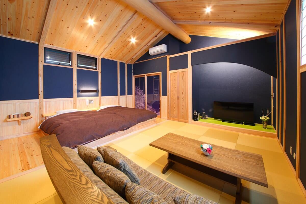 A cozy room with a bed, a sofa, a table, and a TV.