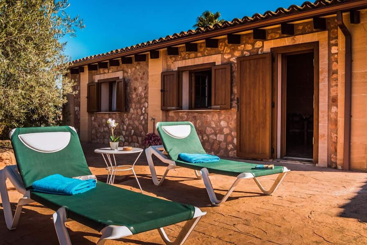 Un bâtiment en pierre avec deux fauteuils et une petite table sur laquelle est posée une plante.