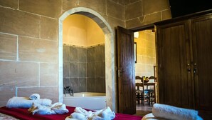 Een badkamer met een stenen muur, een bad en handdoeken op een rode mat.