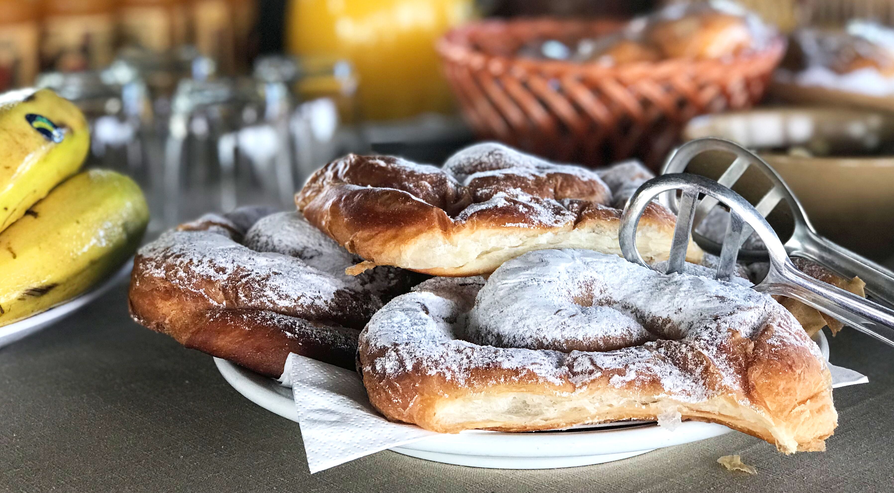 A plate of powdered doughnuts with a dusting of powdered sugar.