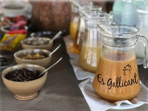 Une table sur laquelle se trouvent divers aliments et une carafe portant l’inscription « Es Galllicant ».