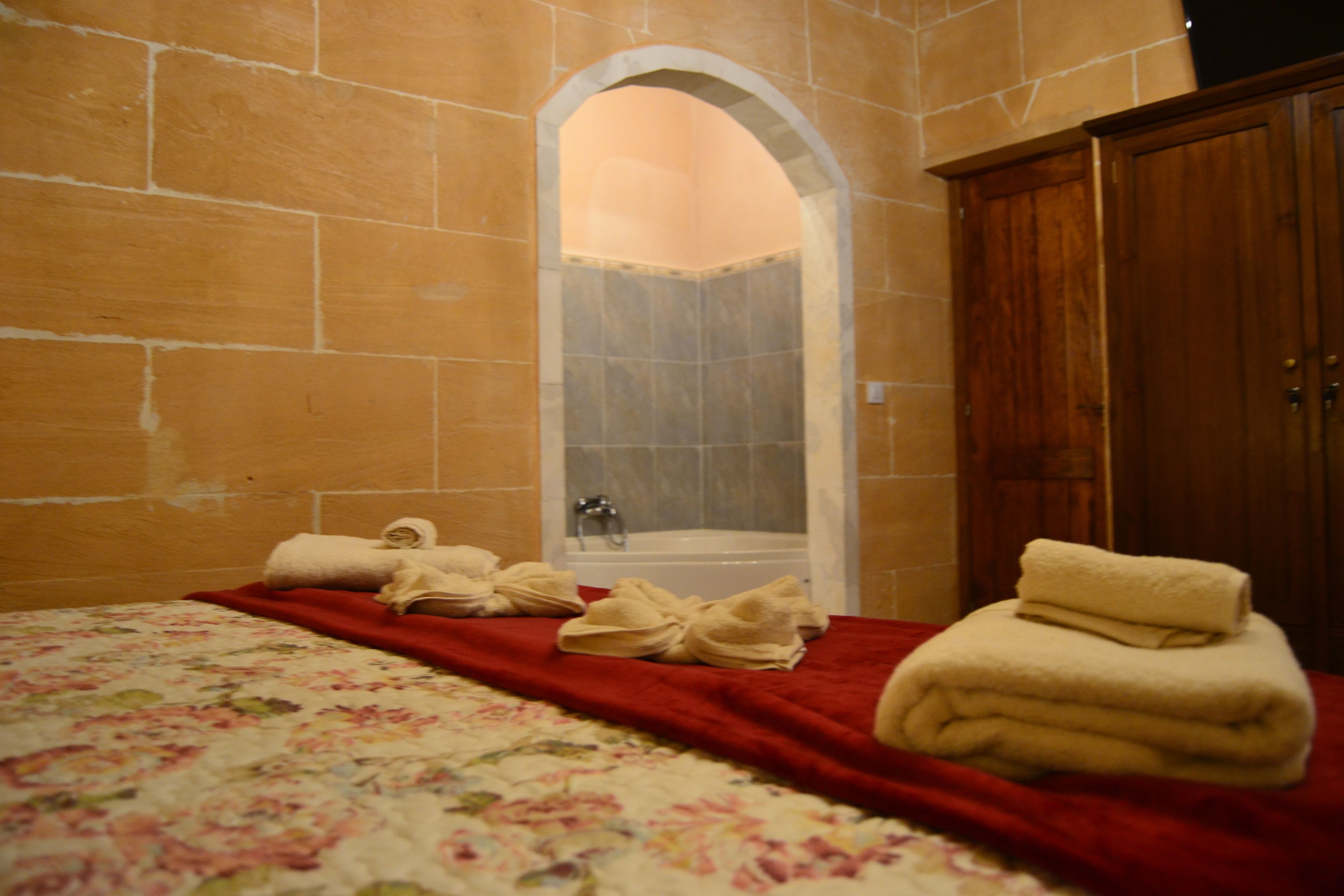 A room with a bed, a red blanket, and a wooden wardrobe.