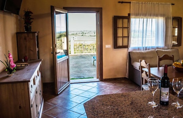Una cocina con comedor y vistas al exterior, además de una botella de vino sobre la mesa.