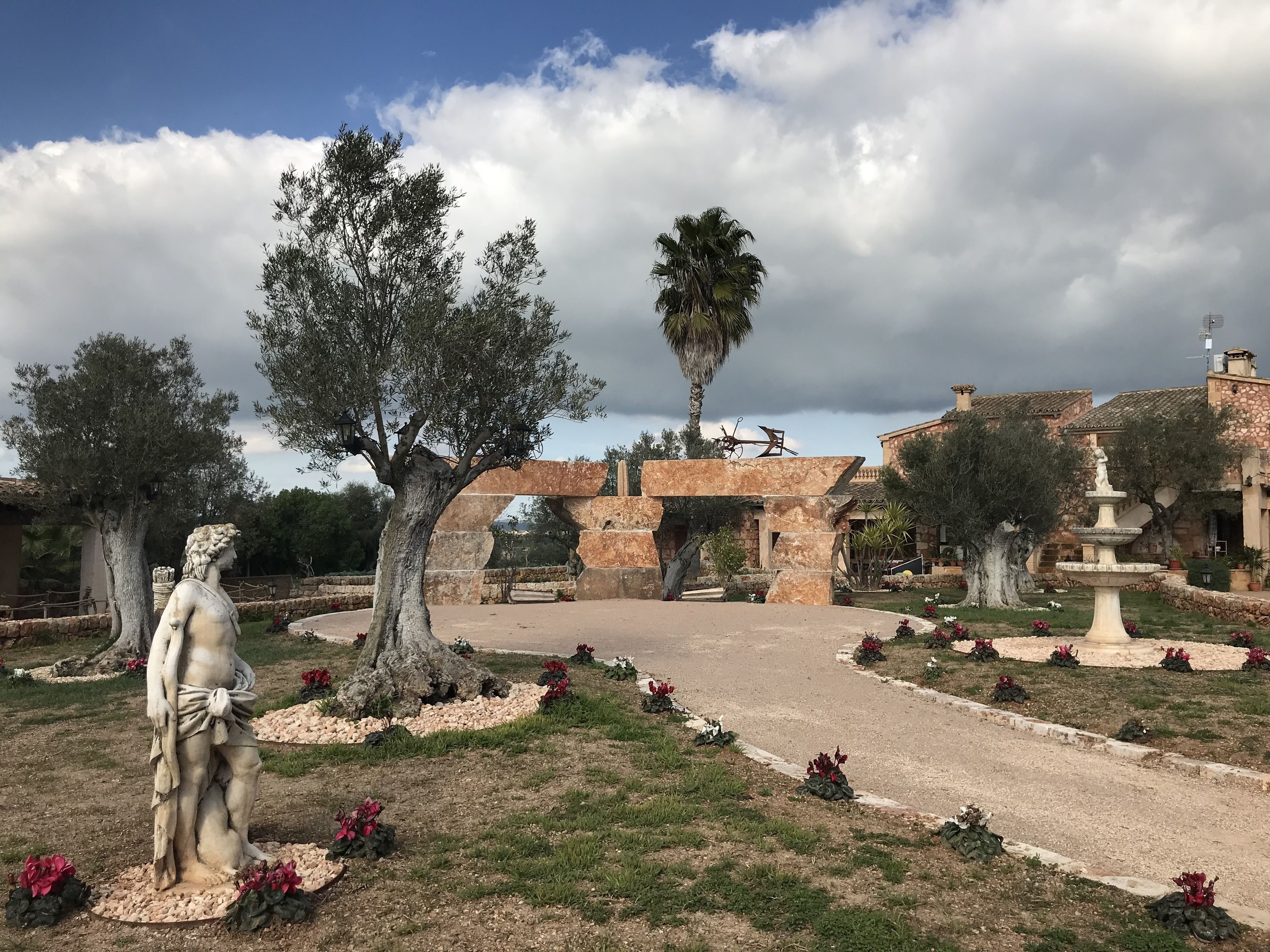 A garden with a statue, a fountain, and stone structures.