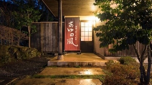 A traditional Japanese building with a wooden entrance and a red banner with white text. - Ayunokaze (Ito)