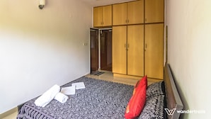A room with a bed, a wardrobe, a ceiling fan, and a door leading to another room. - Luxury Apartment in Indiranagar (Bengaluru)
