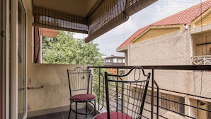 A balcony with two chairs and a view of the surrounding buildings. - Luxury Apartment in Indiranagar (Bengaluru)